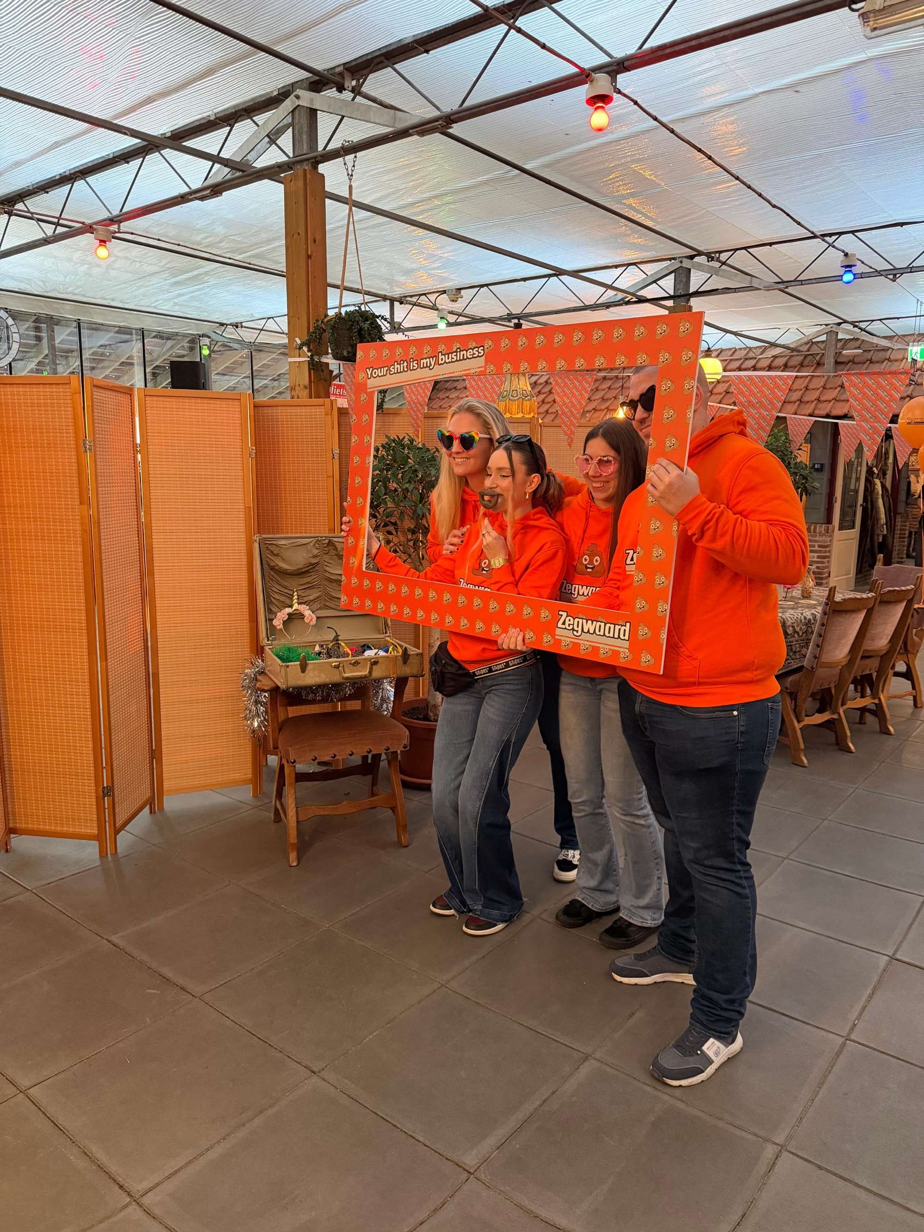 Collega’s in het oranje poseren met een groot fotokader bij de Fotospiegel